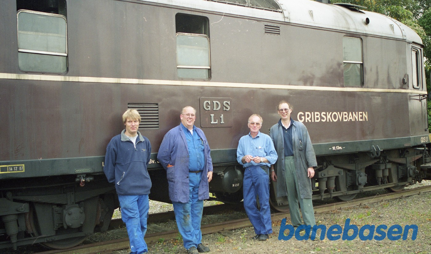 De glade klubmedlemmer foran deres nye lokomotiv på et sidespor i Gilleleje, hvor det skal overvintre i et presenningstelt De glade klubmedlemmer foran deres nye lokomotiv på et sidespor i Gilleleje, hvor det skal overvintre i et presenningstelt