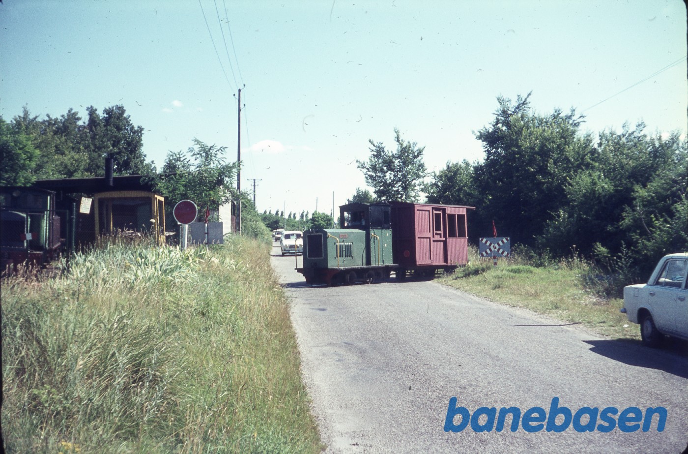Motorlokomotiv med en vogn, krydser vejen Motorlokomotiv med en vogn, krydser vejen