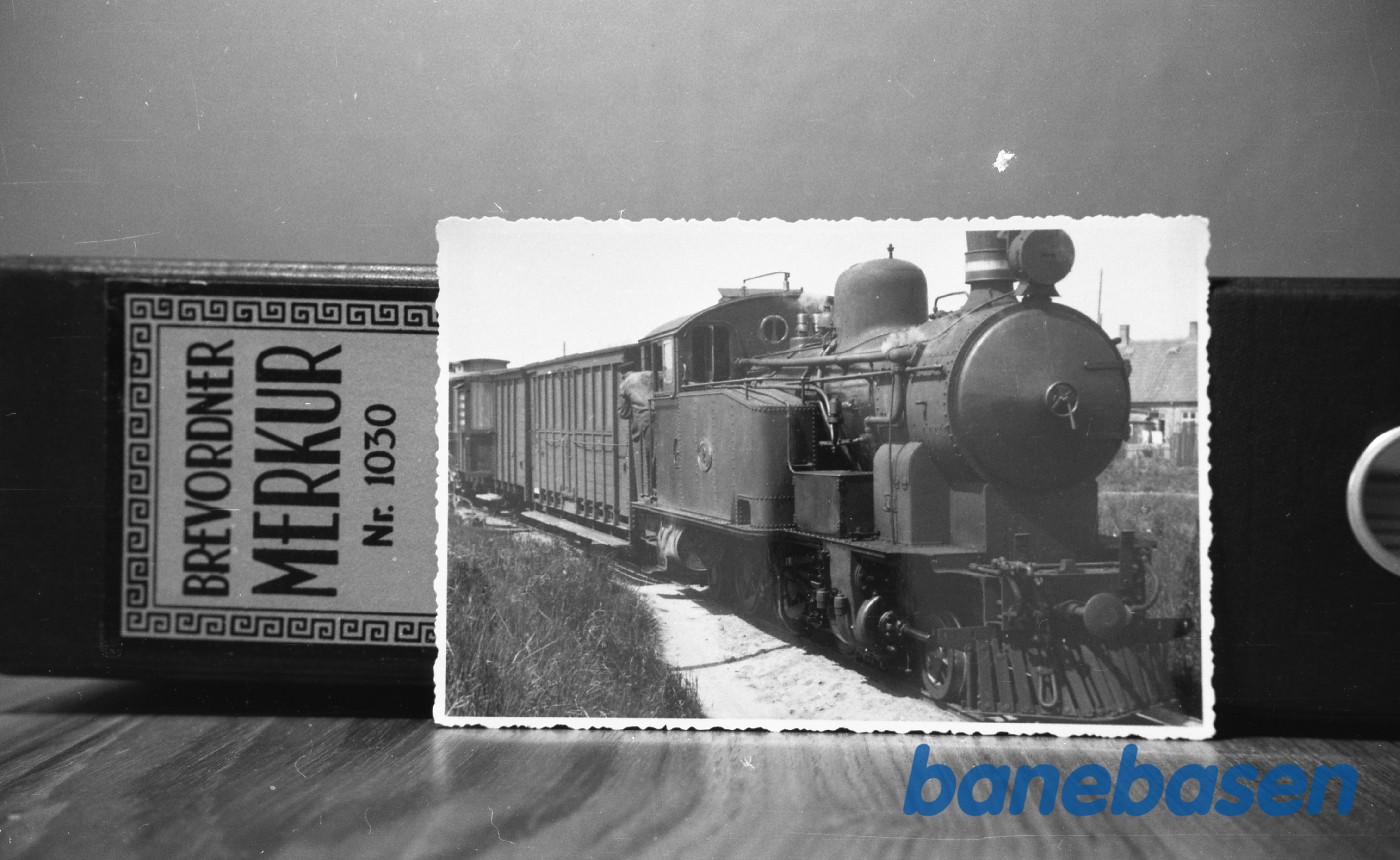 Et langt tog mod Nexø er i sommeren 1944 nået til Rønne N, hvor lokomotivet må holde langt forbi perronen Et langt tog mod Nexø er i sommeren 1944 nået til Rønne N, hvor lokomotivet må holde langt forbi perronen