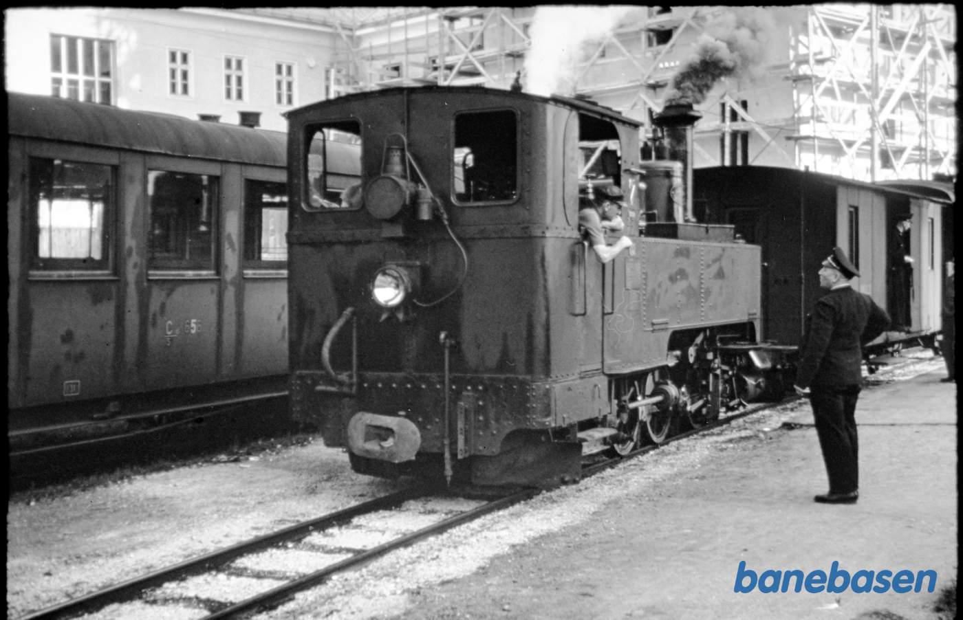 Damplokomotiv med person og pakvogne holder ved en perron