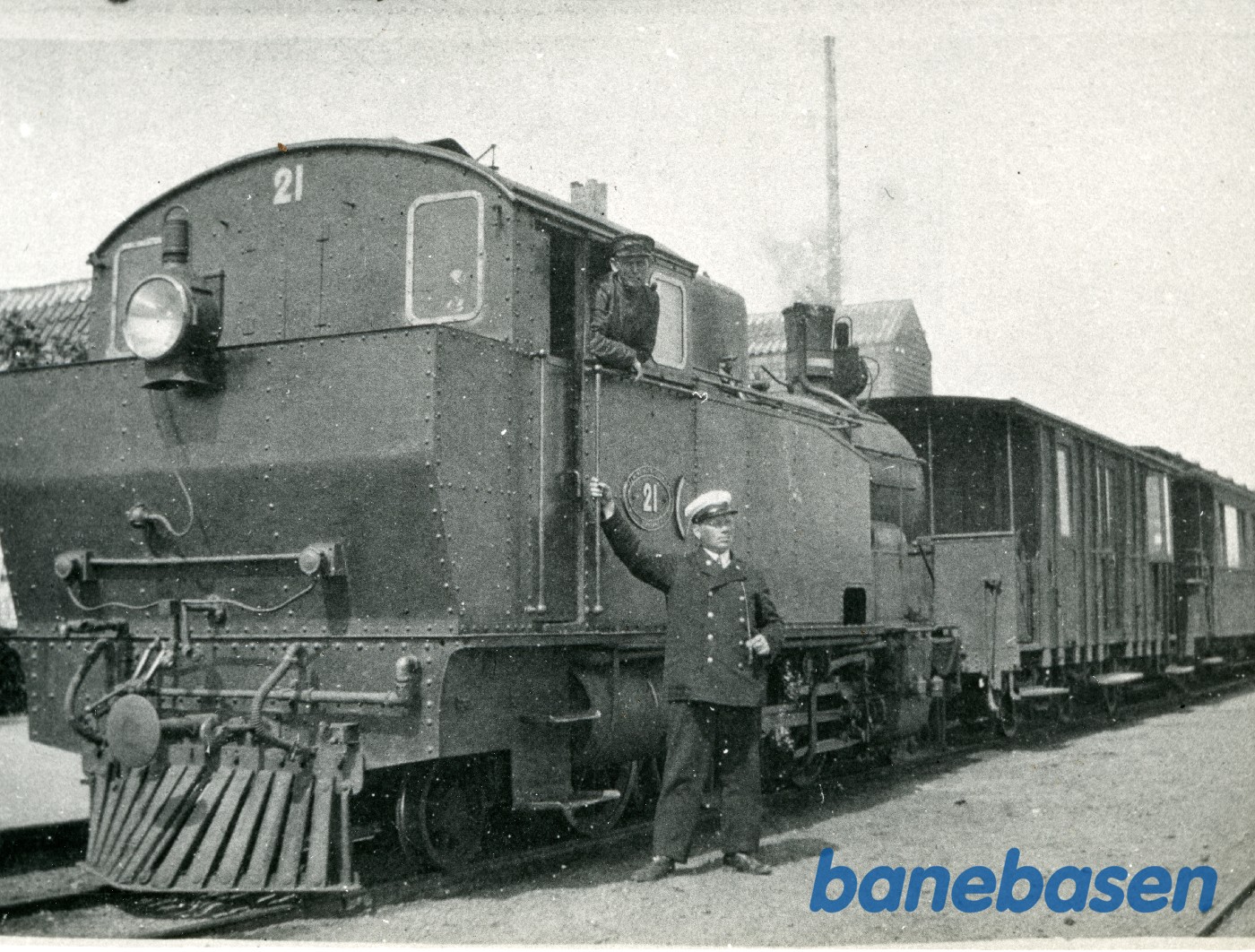 Gudhjem-banens lokomotiv nr. 21 på Gudhjem station, som ses bag toget. Portør Henry Clausen ved siden af lokomotivet Gudhjem-banens lokomotiv nr. 21 på Gudhjem station, som ses bag toget. Portør Henry Clausen ved siden af lokomotivet