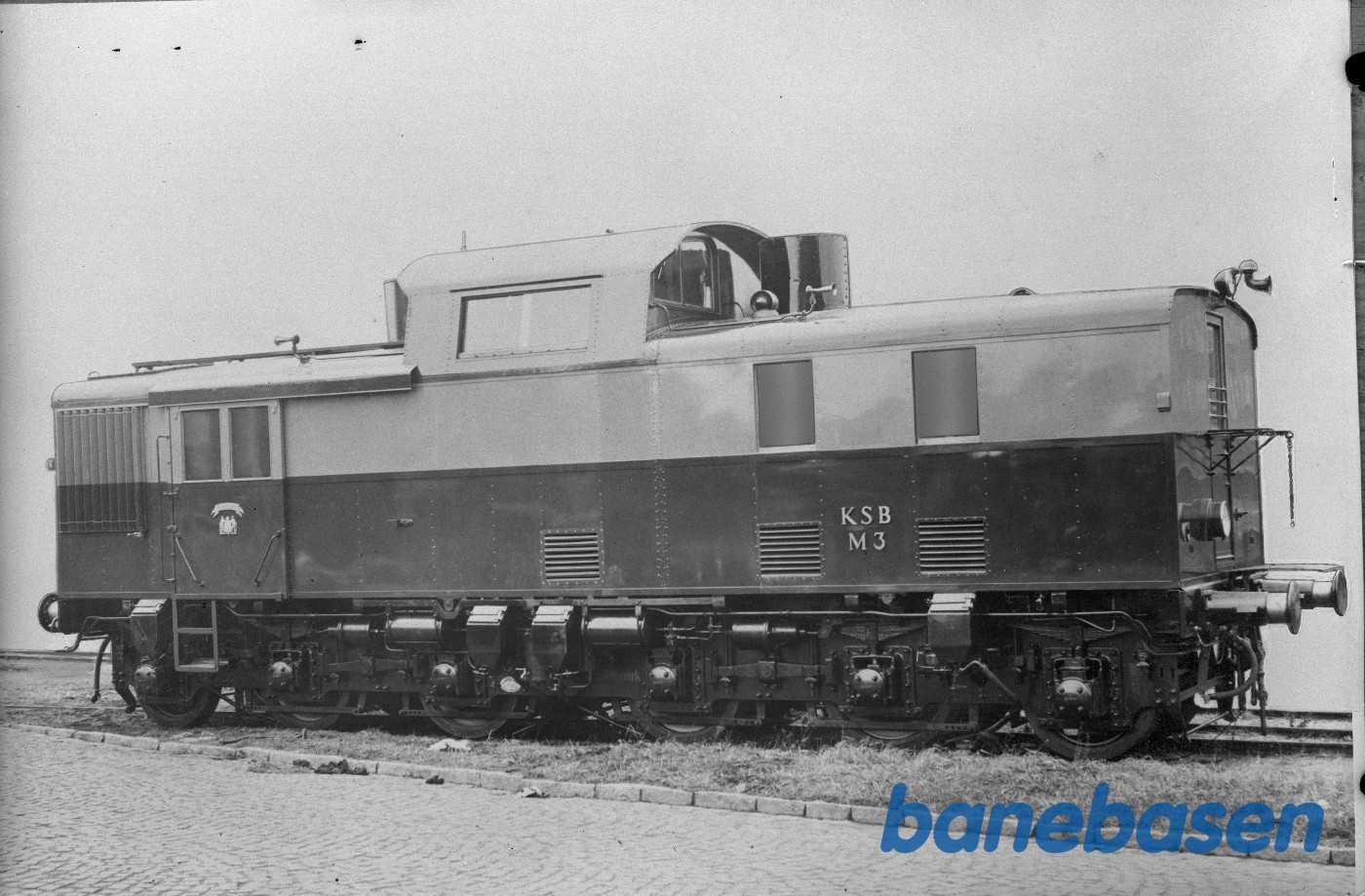 Retoucheret foto af KSB M 3 som fra B&Ws lokomotivmotorværksted netop har krydset Scandiagade Retoucheret foto af KSB M 3 som fra B&Ws lokomotivmotorværksted netop har krydset Scandiagade