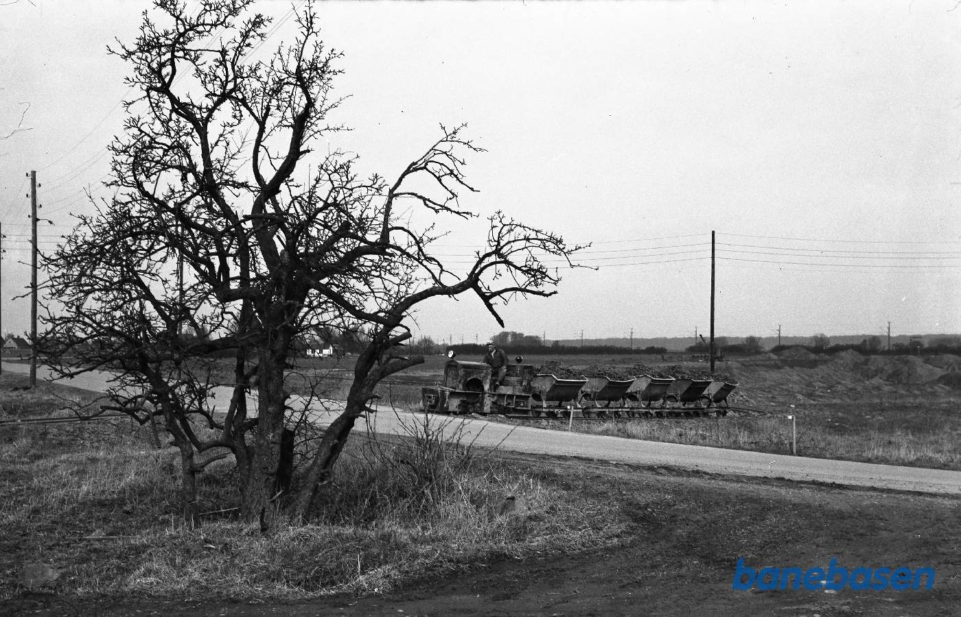 motorlokomotiv med vogne passerer vej