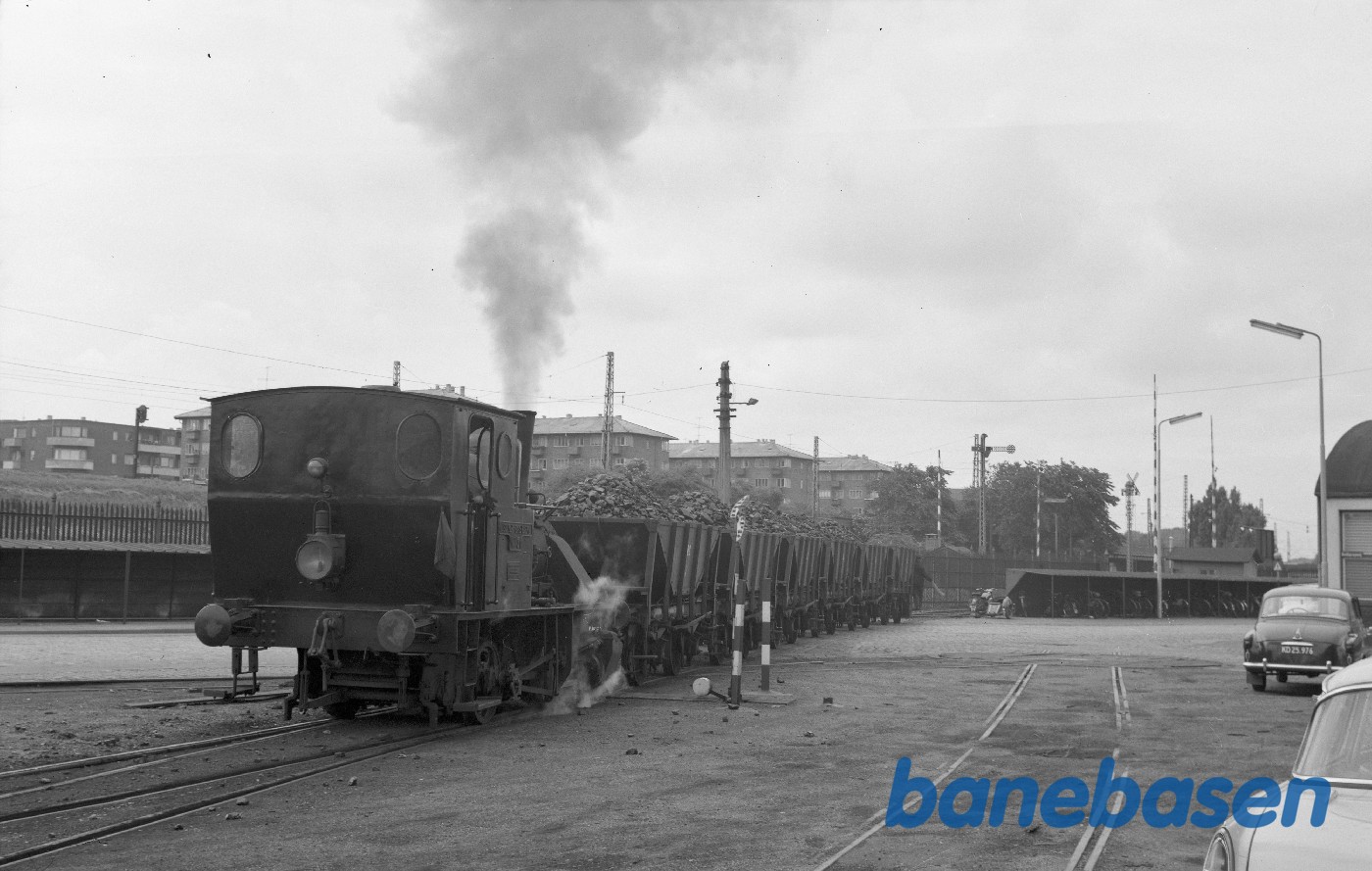 Tog på vej mod gasværket passerer en gade inde i Frihavnen. Kalkbrænderihavnsgade på den anden side af hegnet og bommene ved Århusgade ses til højre i billedet Tog på vej mod gasværket passerer en gade inde i Frihavnen. Kalkbrænderihavnsgade på den anden side af hegnet og bommene ved Århusgade ses til højre i billedet