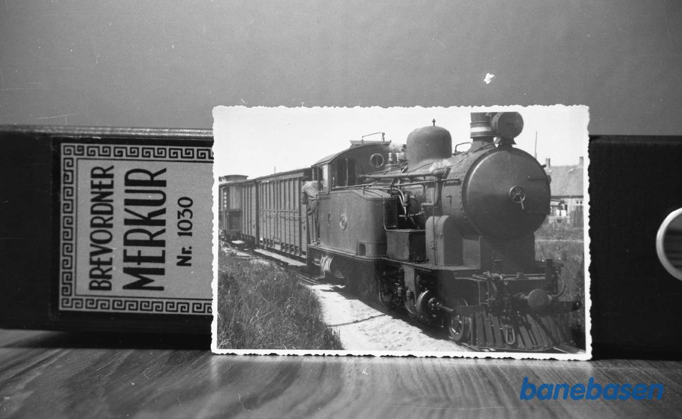 Et langt tog mod Nexø er i sommeren 1944 nået til Rønne N, hvor lokomotivet må holde langt forbi perronen Et langt tog mod Nexø er i sommeren 1944 nået til Rønne N, hvor lokomotivet må holde langt forbi perronen