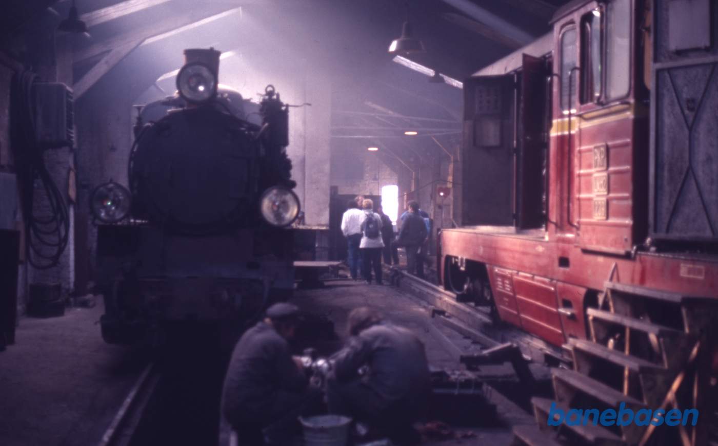 Håndværkere arbejder i værkstedet mens gæsterne midt i billedet vises rundt