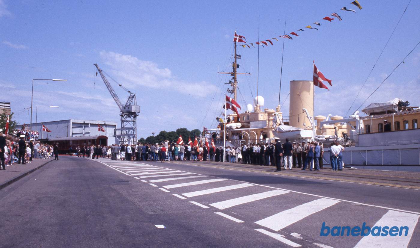 Toget er ankommet til Kongekajen i Helsingør. Kongevognen ses ude i horisonten og kongeskibet Dannebrog til højre