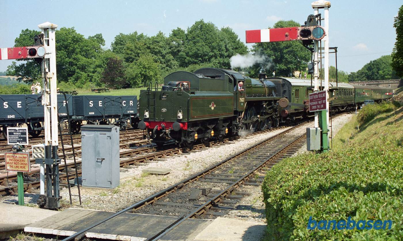 Et armsignal i forgrunden og et persontog på vej ind på stationen