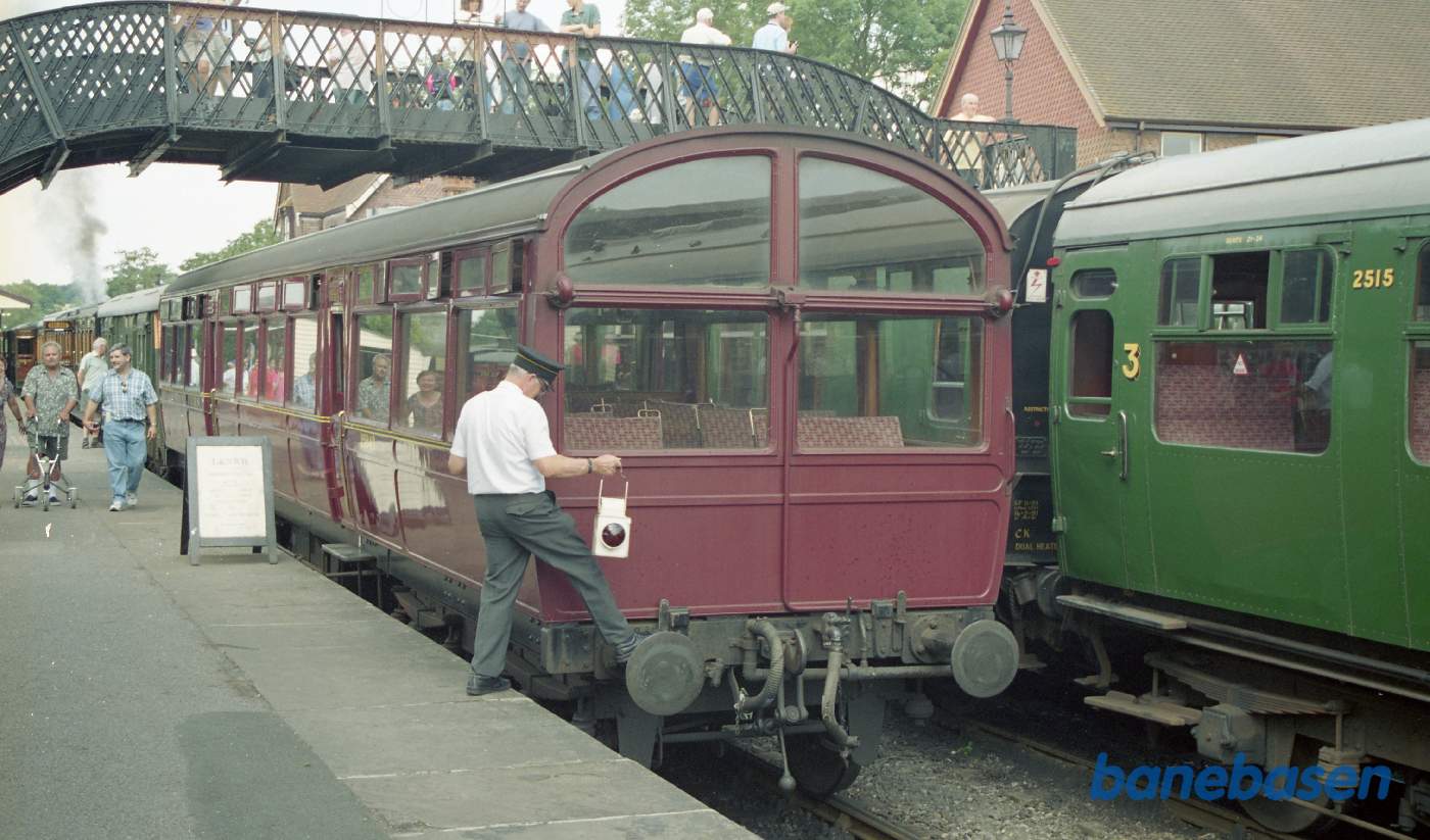 Rangerlederen hænger rød slutlampe bag på toget. En travl dag med tog i begge perronspor
