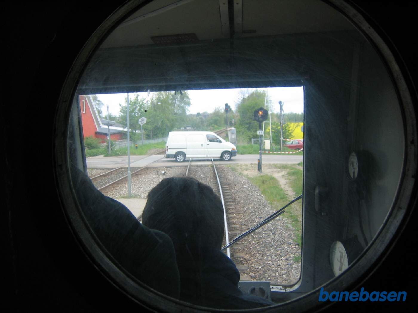 Billede ud gennem koøjet i væggen mellem motorrummet og førerrummet. Varevogn krydser banen i overkørsel 47 på Græsted station Billede ud gennem koøjet i væggen mellem motorrummet og førerrummet. Varevogn krydser banen i overkørsel 47 på Græsted station