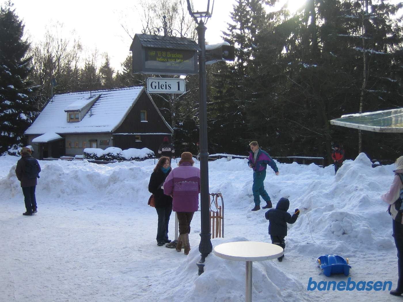 Nogle rejsende står i sneen og et barn med sin blå plastkælk