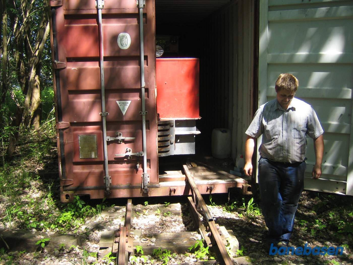 Et motorlokomotiv i en container, anvendt som remise, en medarbejder i gang med at åbne containeren