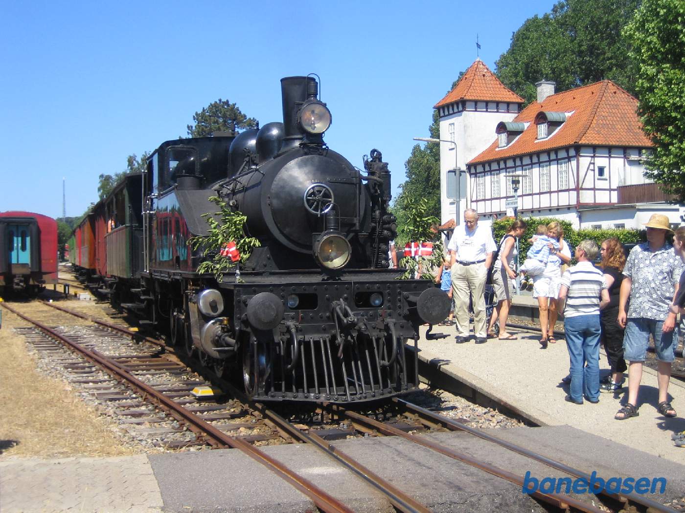 Damptoget ankommet til Grønnehave, hvor passagererne stiger ud og kigger på det fint pyntede damplokomotiv Damptoget ankommet til Grønnehave, hvor passagererne stiger ud og kigger på det fint pyntede damplokomotiv