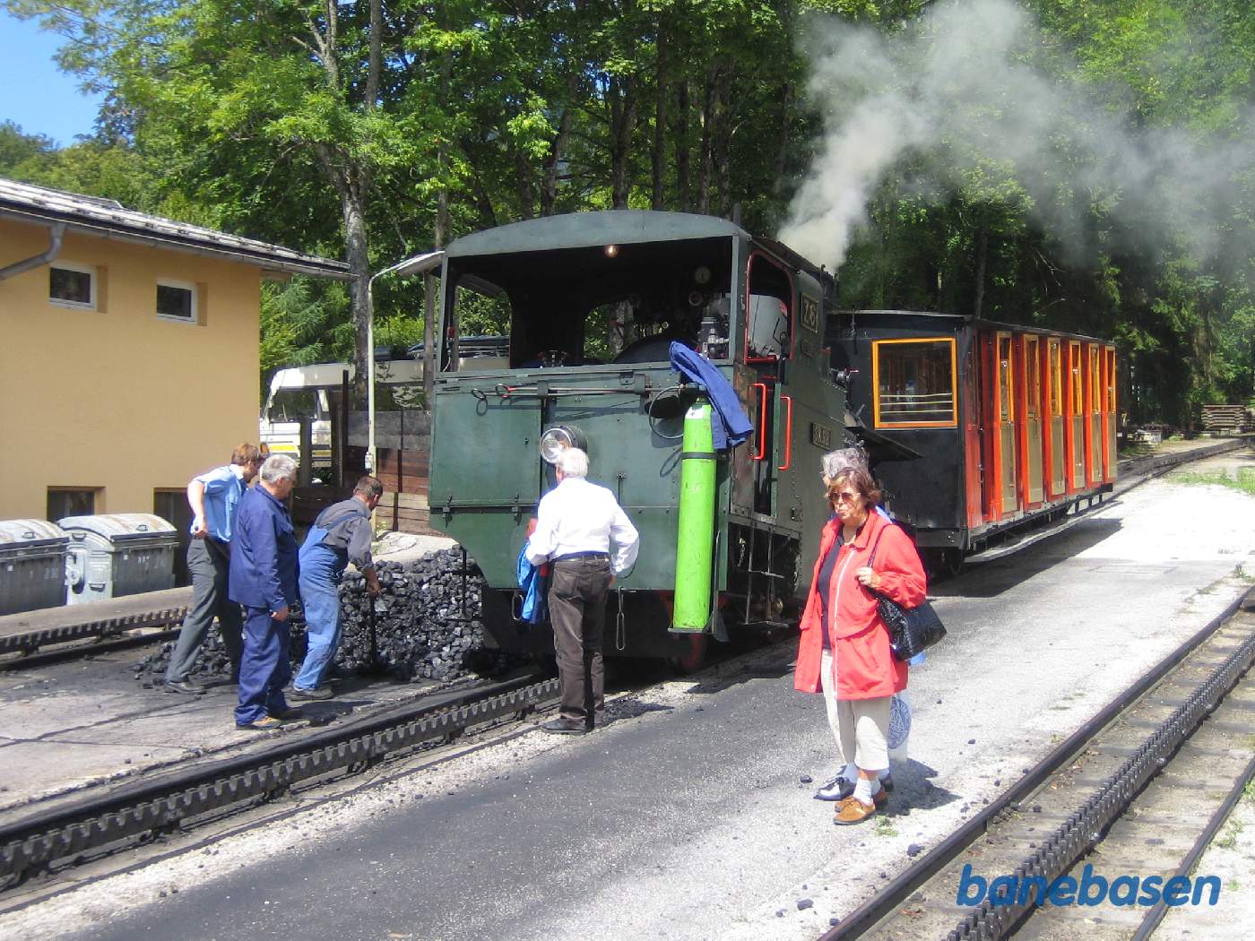 Der skovles kul på lokomotivet mens nogle turister ser på