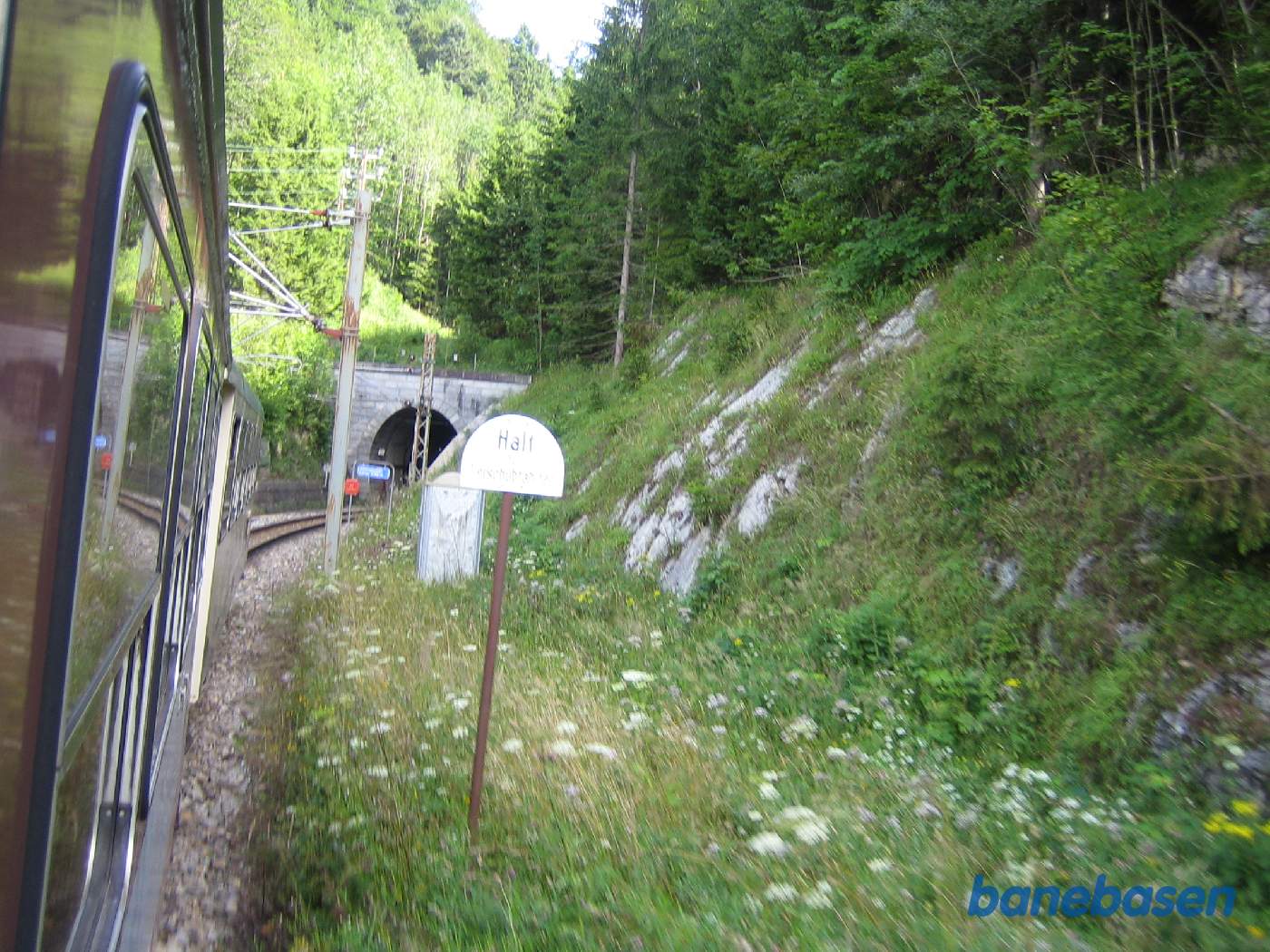 Toget kører i et kuperet landskab, her på vej ud af en tunnel