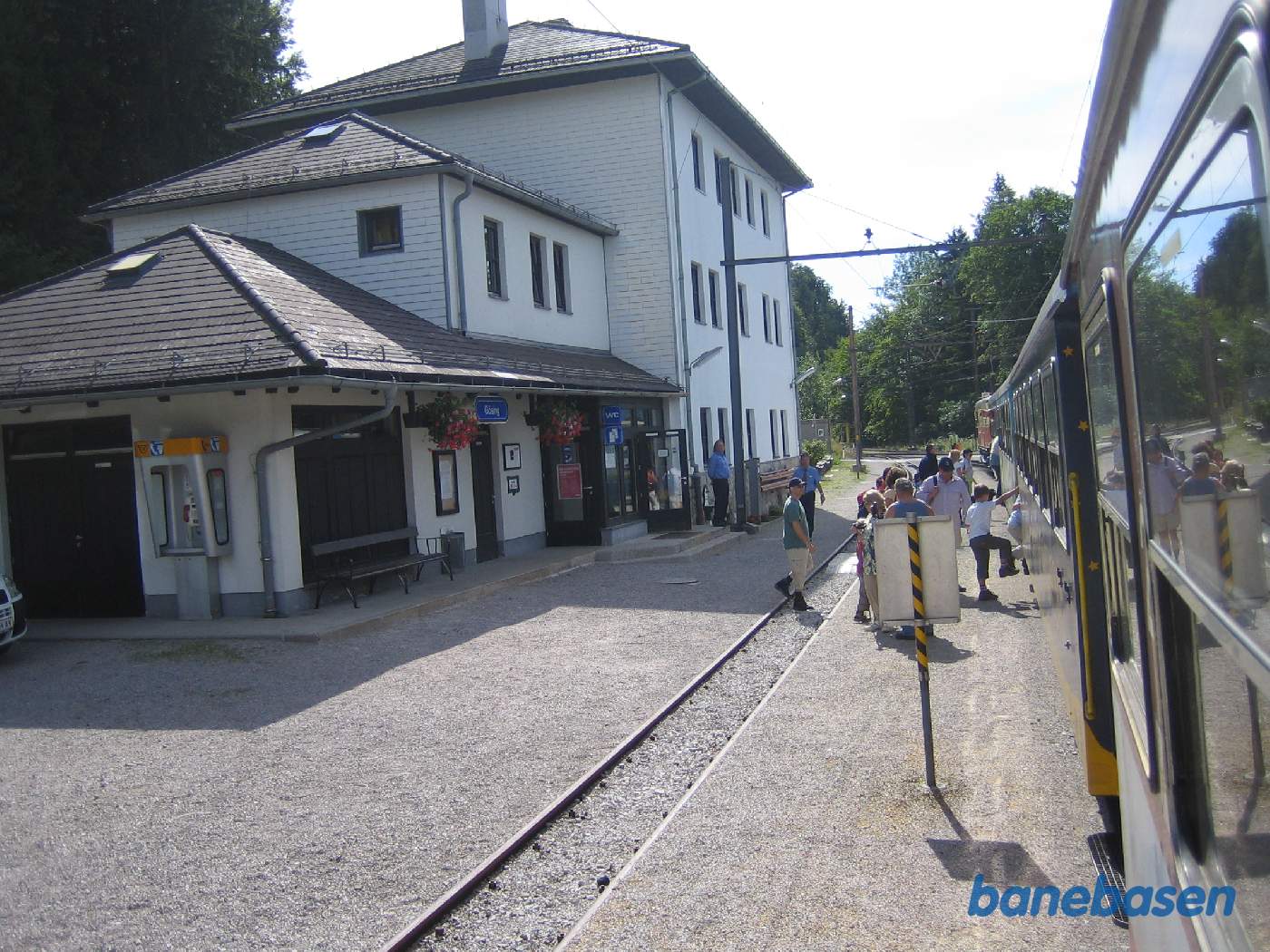 En del rejsende stiger på toget, stationsbygningen til venstre