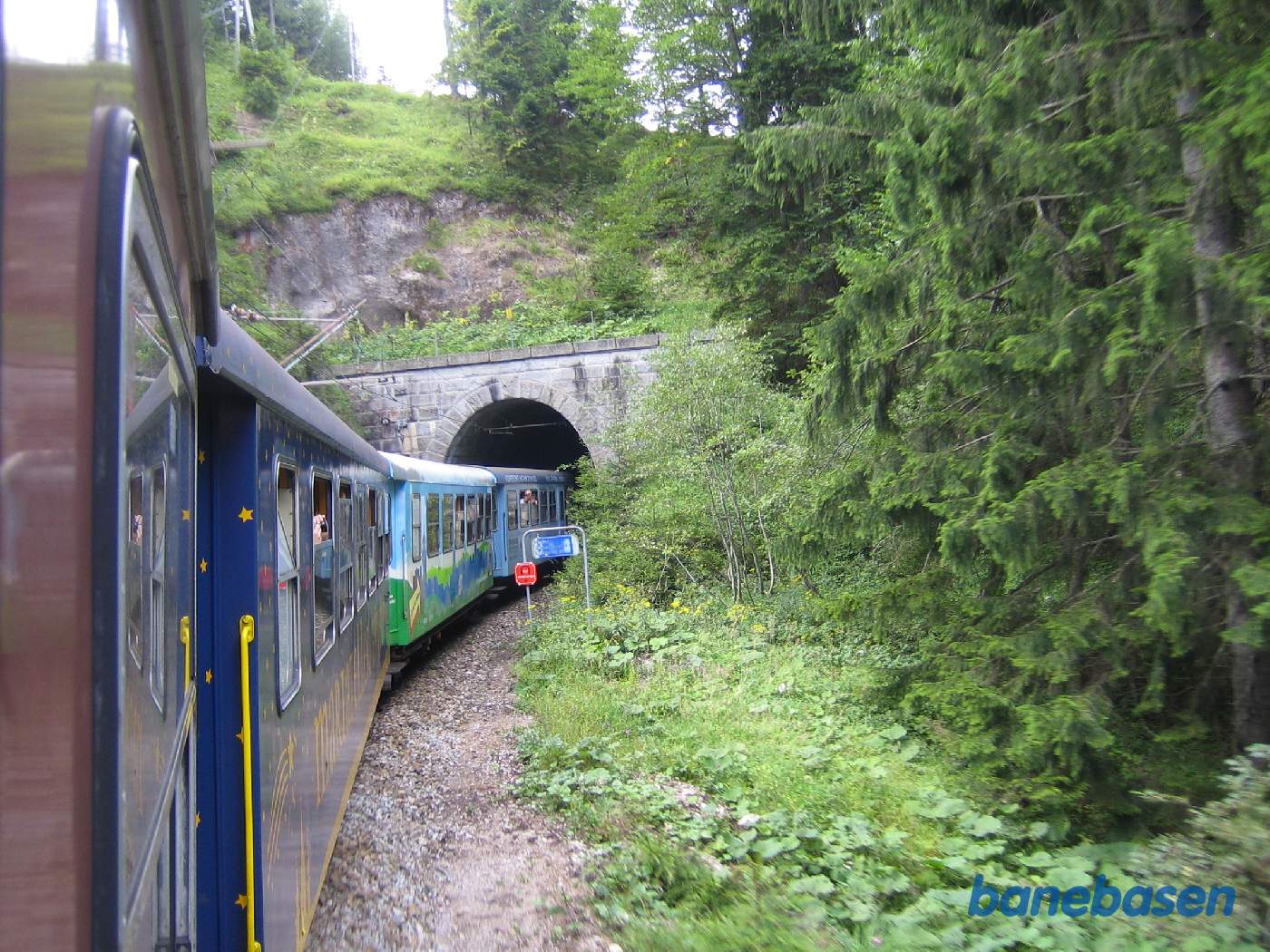 Toget kører i et kuperet landskab, her på vej ind i en tunnel