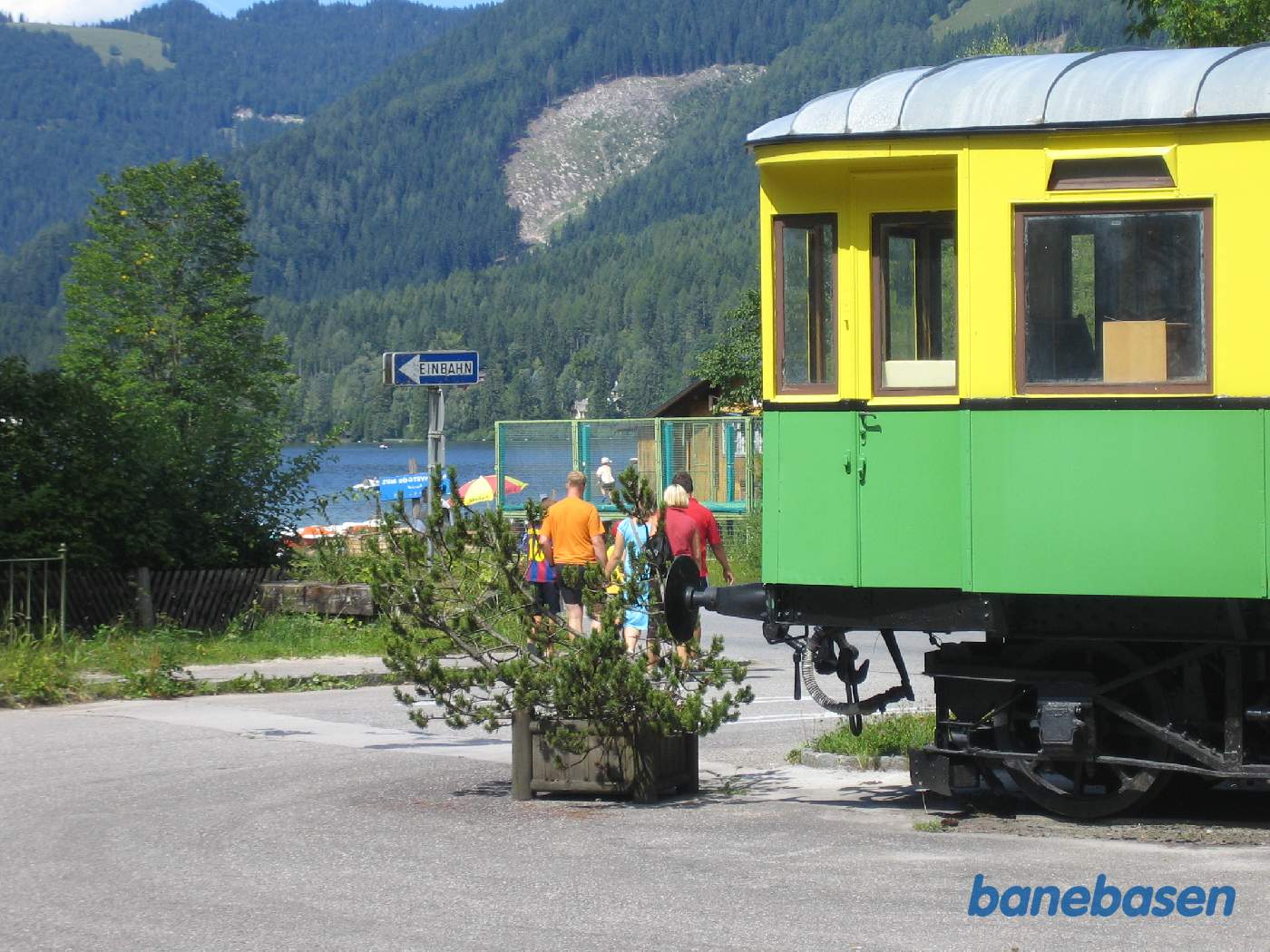 En grøn-gul vogn udstillet på en sporramme, søen (Erlaufsee) ses i baggrunden