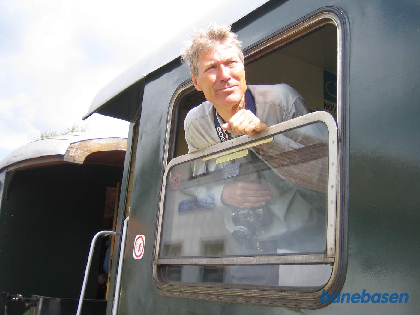 Persontoget holder ved perron. En turist kigger interesseret ud af vinduet