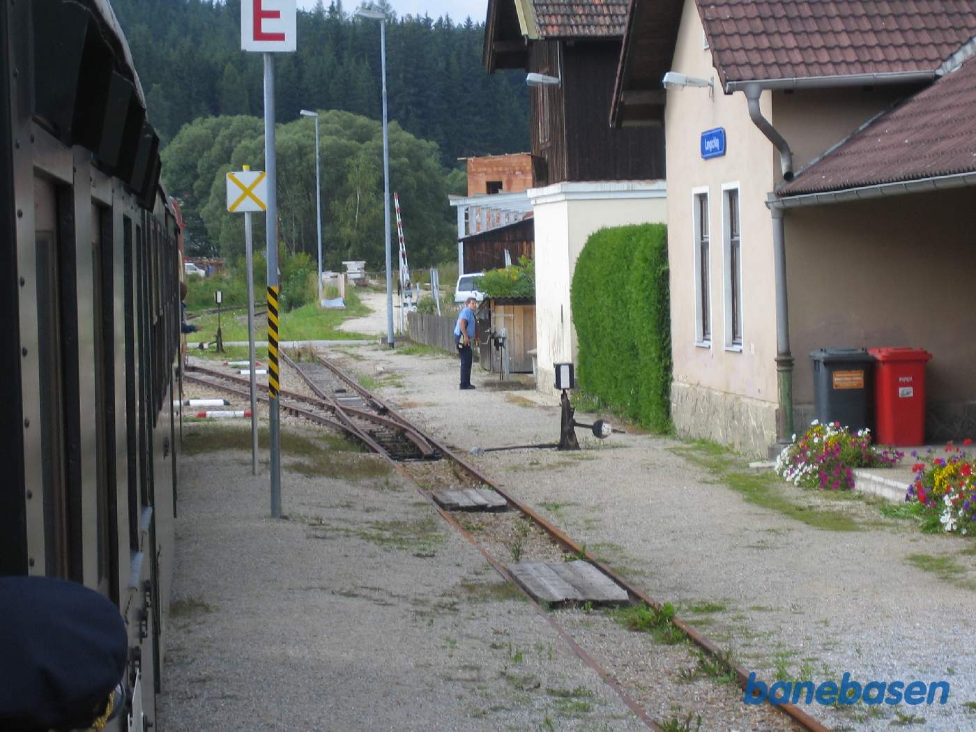 Persontoget er klar til at køre videre. Stationsforstanderen i gang med at rulle bommen over vejen ned