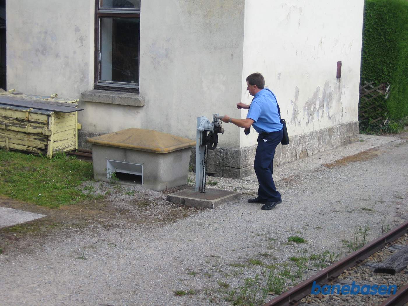 Stationsforstanderen i gang med at rulle bommen over vejen ned