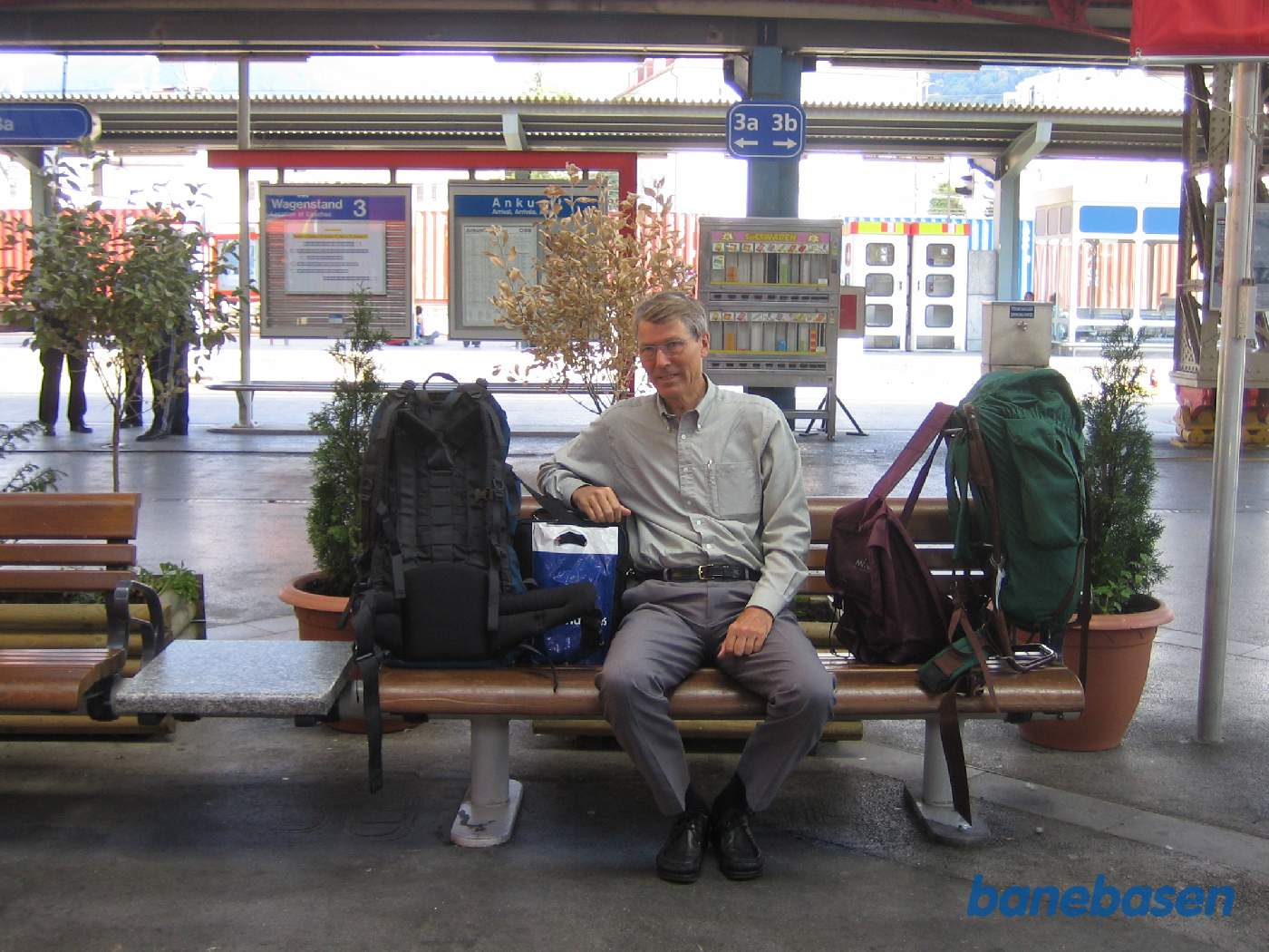 En turist med oppakning sidder på en bænk og venter på næste tog