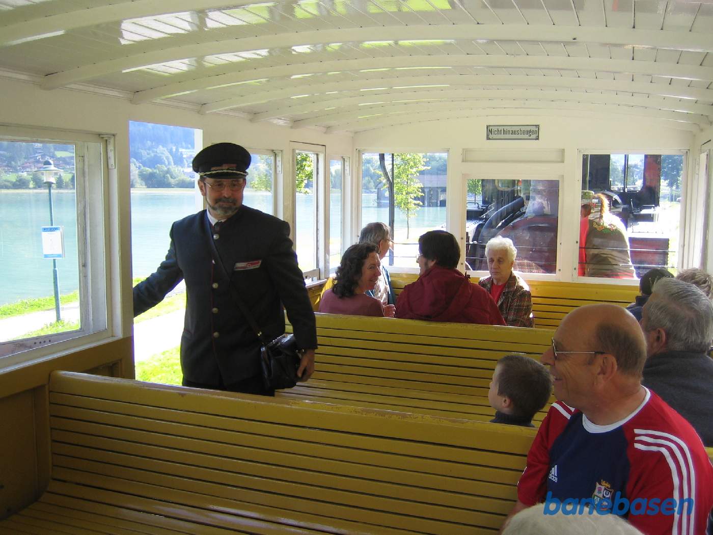 Konduktøren tjekker billetter lige inden afgang fra stationen. Søens blå vand ses til venstre