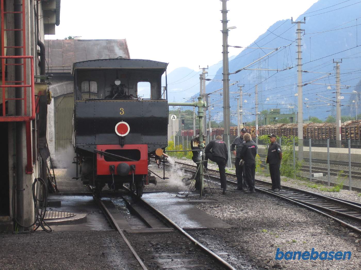 Damplokomotivet holder lige udenfor remisen mens personalet snakker
