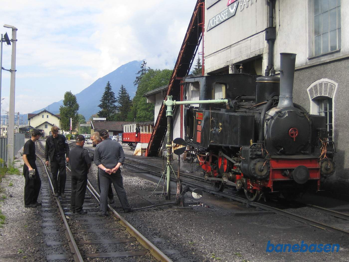 Damplokomotivet holder lige udenfor remisen mens personalet snakker