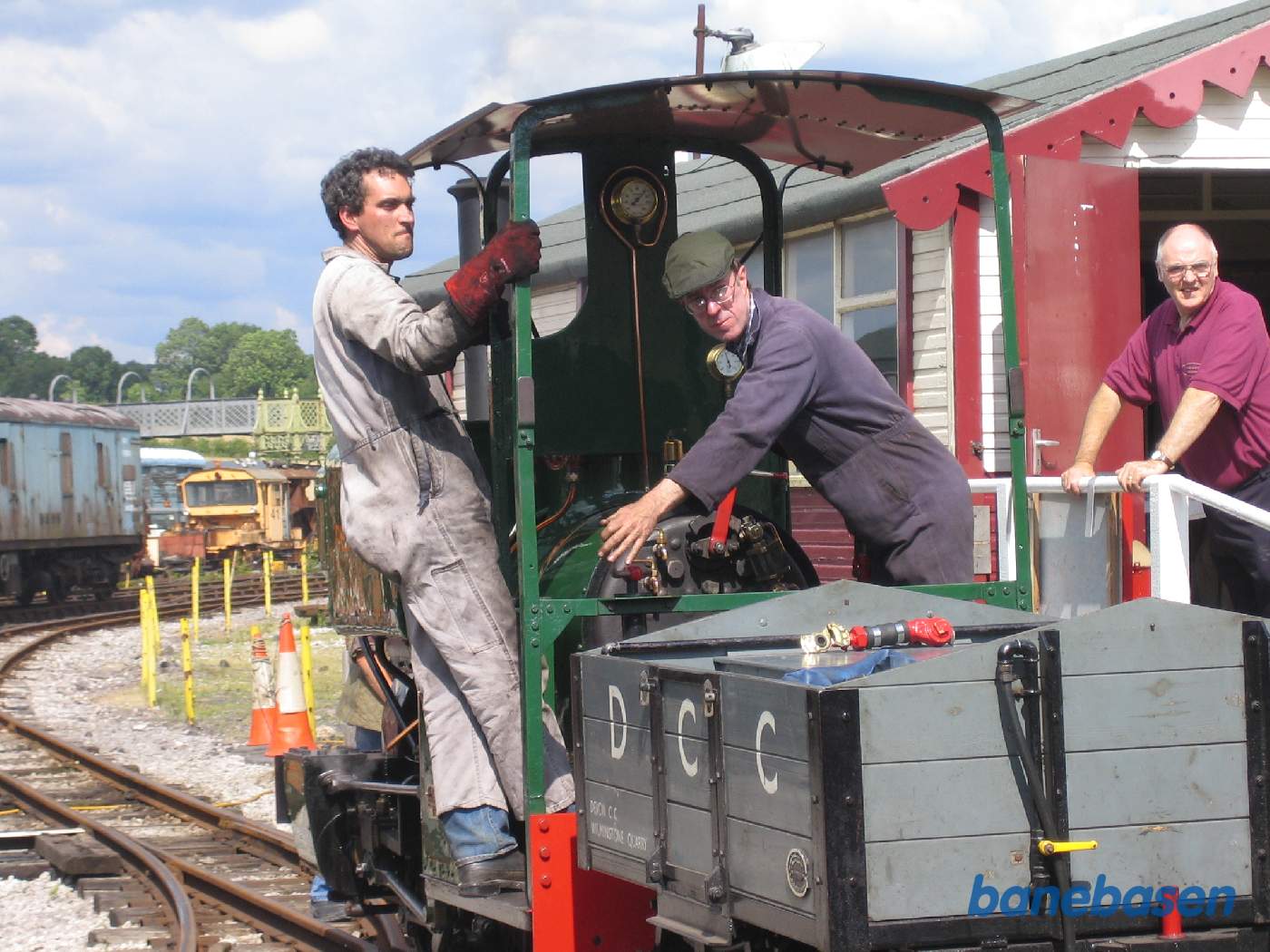 Damplokomotivet rangerer ned mod vognene, stationsbygningen lige bag lokomotivet