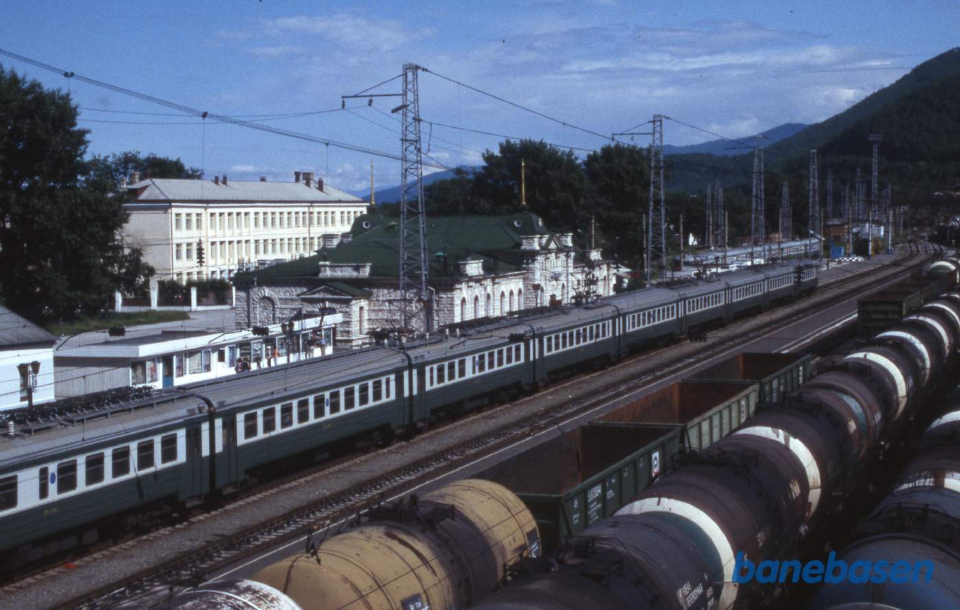 Et persontog holder ved perron, set oppe fra den lange gangbro over jernbanen