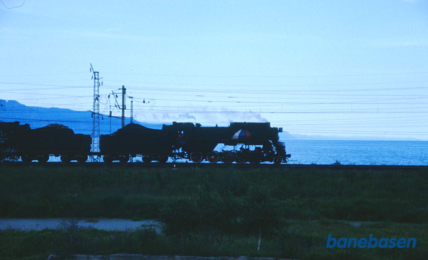 Et udflugtstog med 2 damplokomotiver havde været på tur til Port Baikal og er nu på vej tilbage til Sludyanka en sen eftermiddag. Baikalsøen ses på den anden side af jernbanen