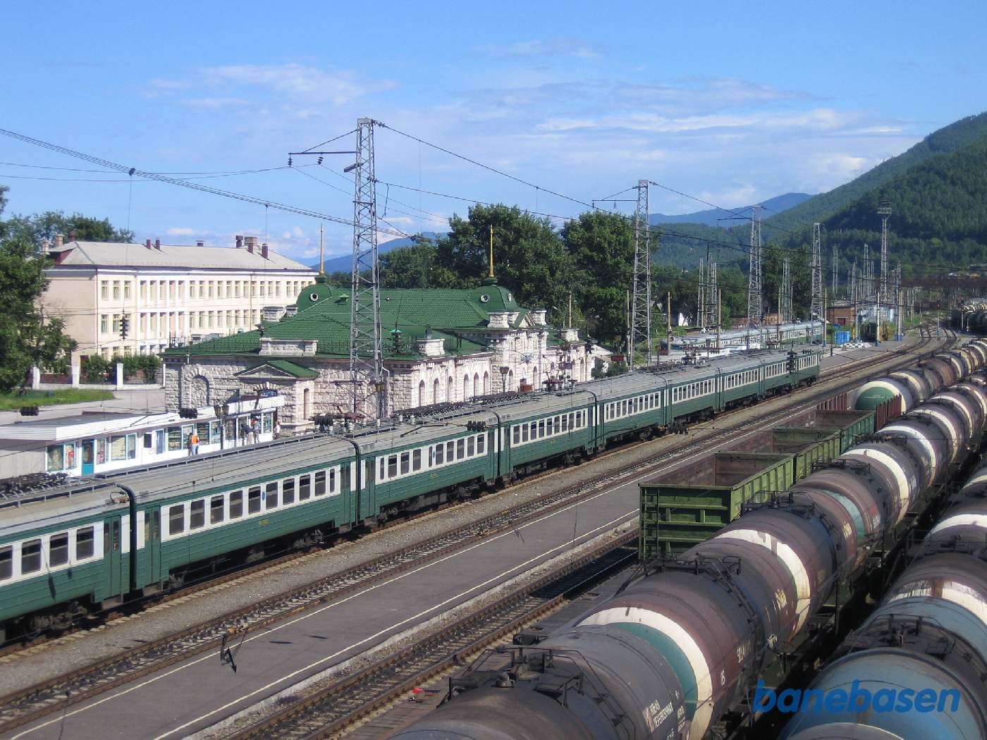 Et persontog holder ved perron, set oppe fra den lange gangbro over jernbanen