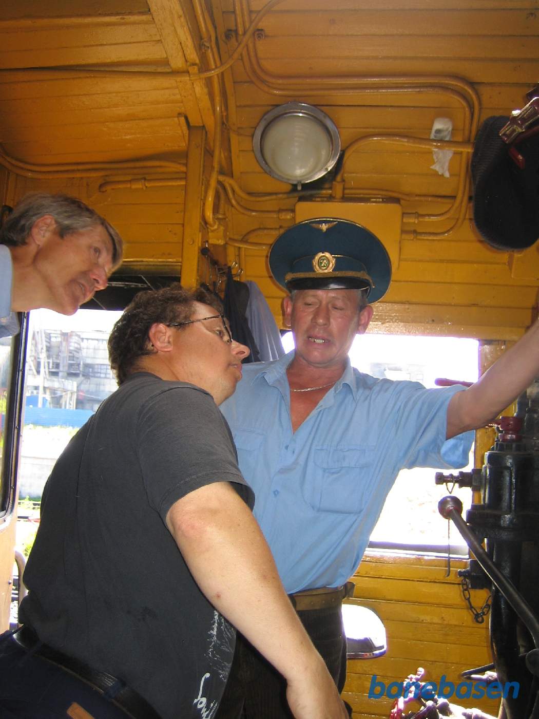 Lokomotivføreren i førerrummet fortæller 2 turister om lokomotivet