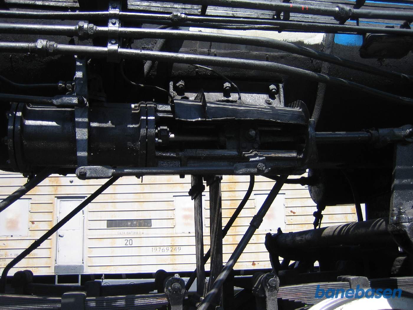 Et billede ind under kedlen, hvor en cylinder kan skubbe til en stang, der har fat i stangen til glideren. Cylinderen bestemmer om lokomotivet skal køre forlæns eller baglæns samt fyldningsgraden i stempelslagene