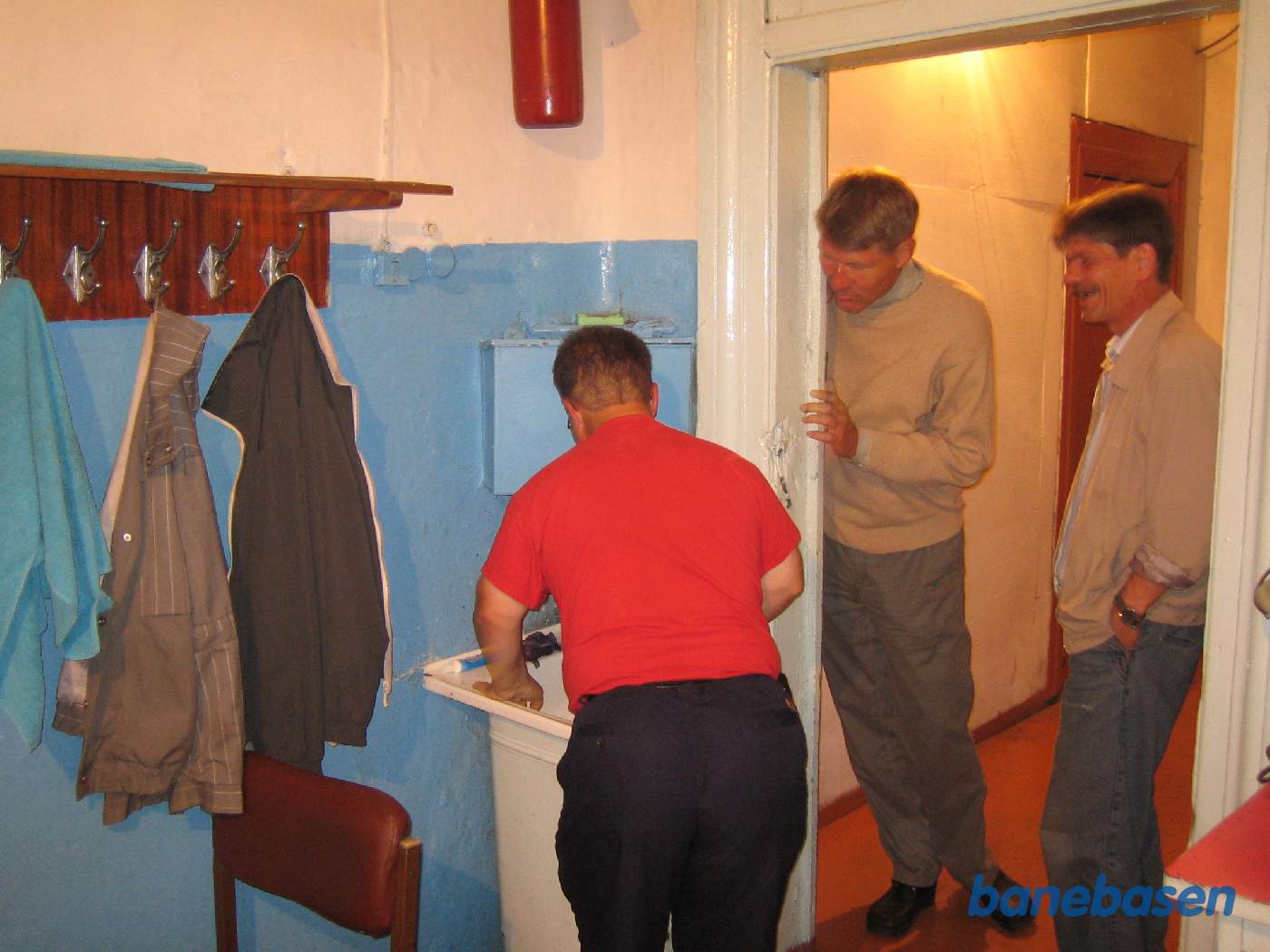 Der børstes tænder ved den lille håndvask, vandbeholderen bag hovedet på den ene turist