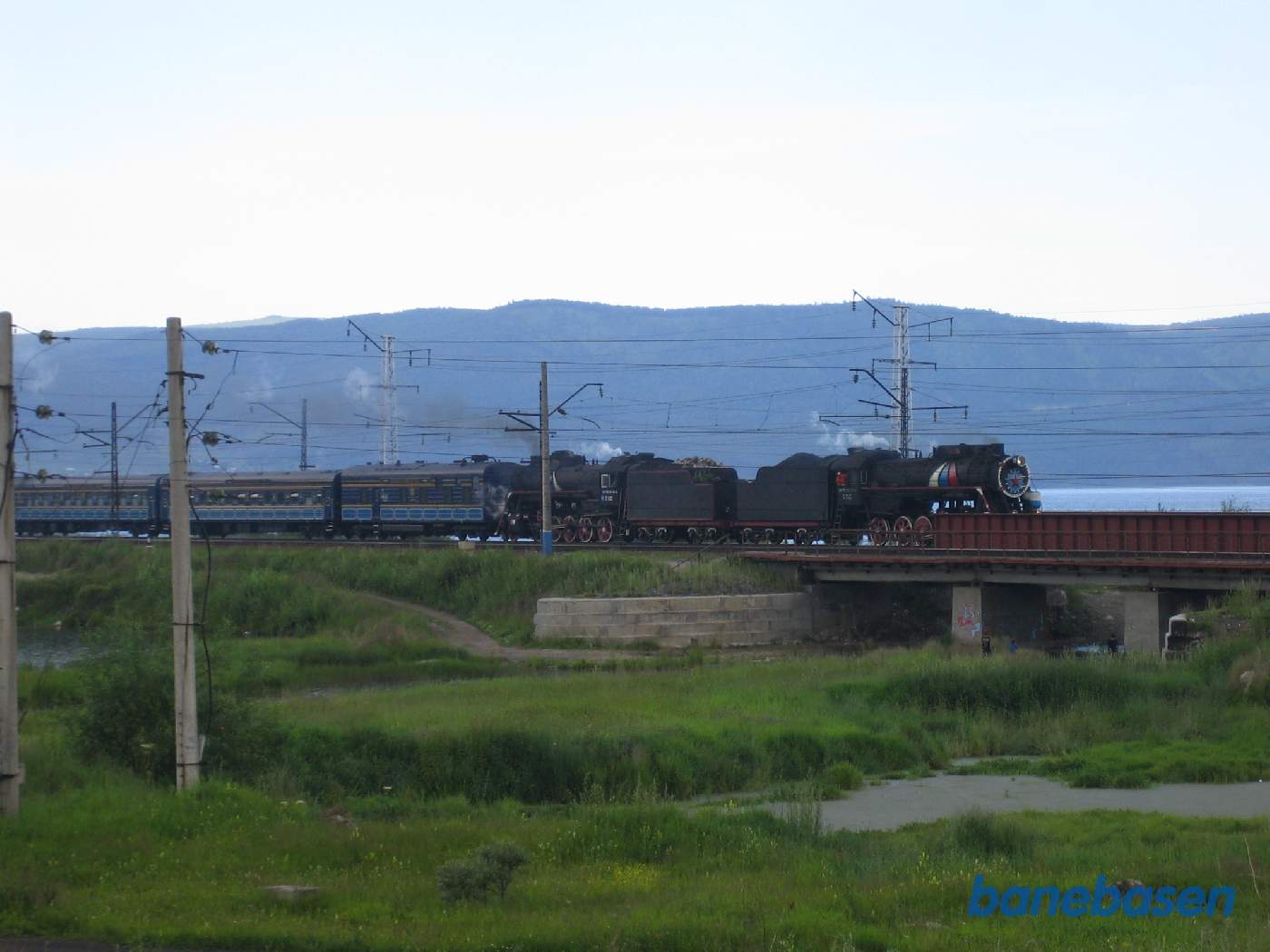 Et turisttog med 2 damplokomotiver fra Port Baikal på vej ind mod Sludyanka station, Baikal søen til højre