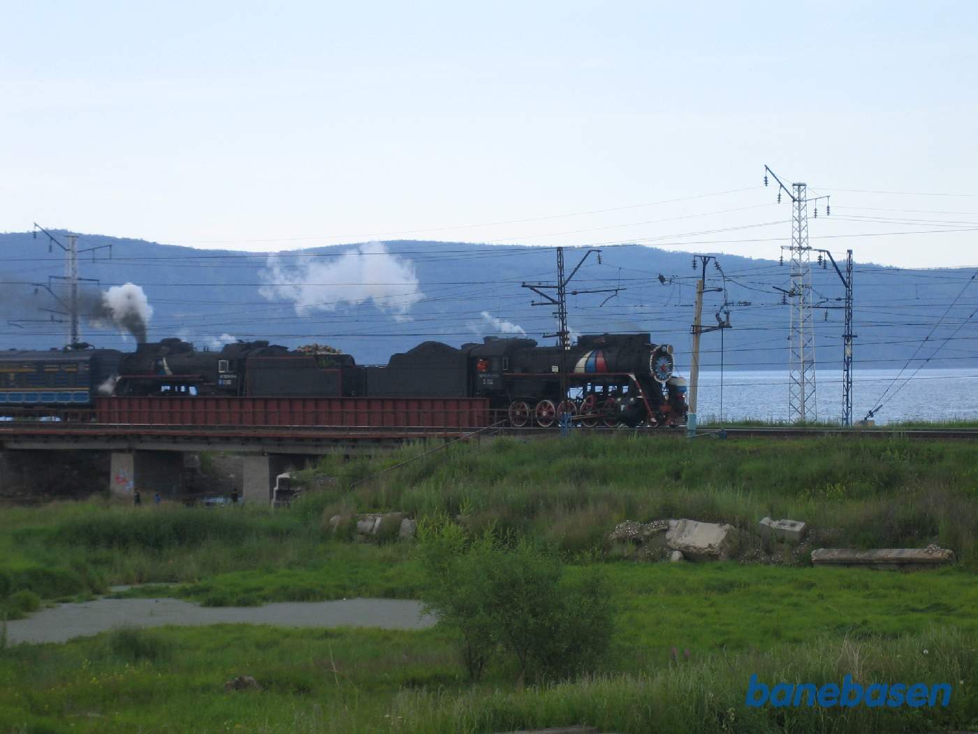 Et turisttog med 2 damplokomotiver fra Port Baikal på vej ind mod Sludyanka station, Baikal søen bag toget