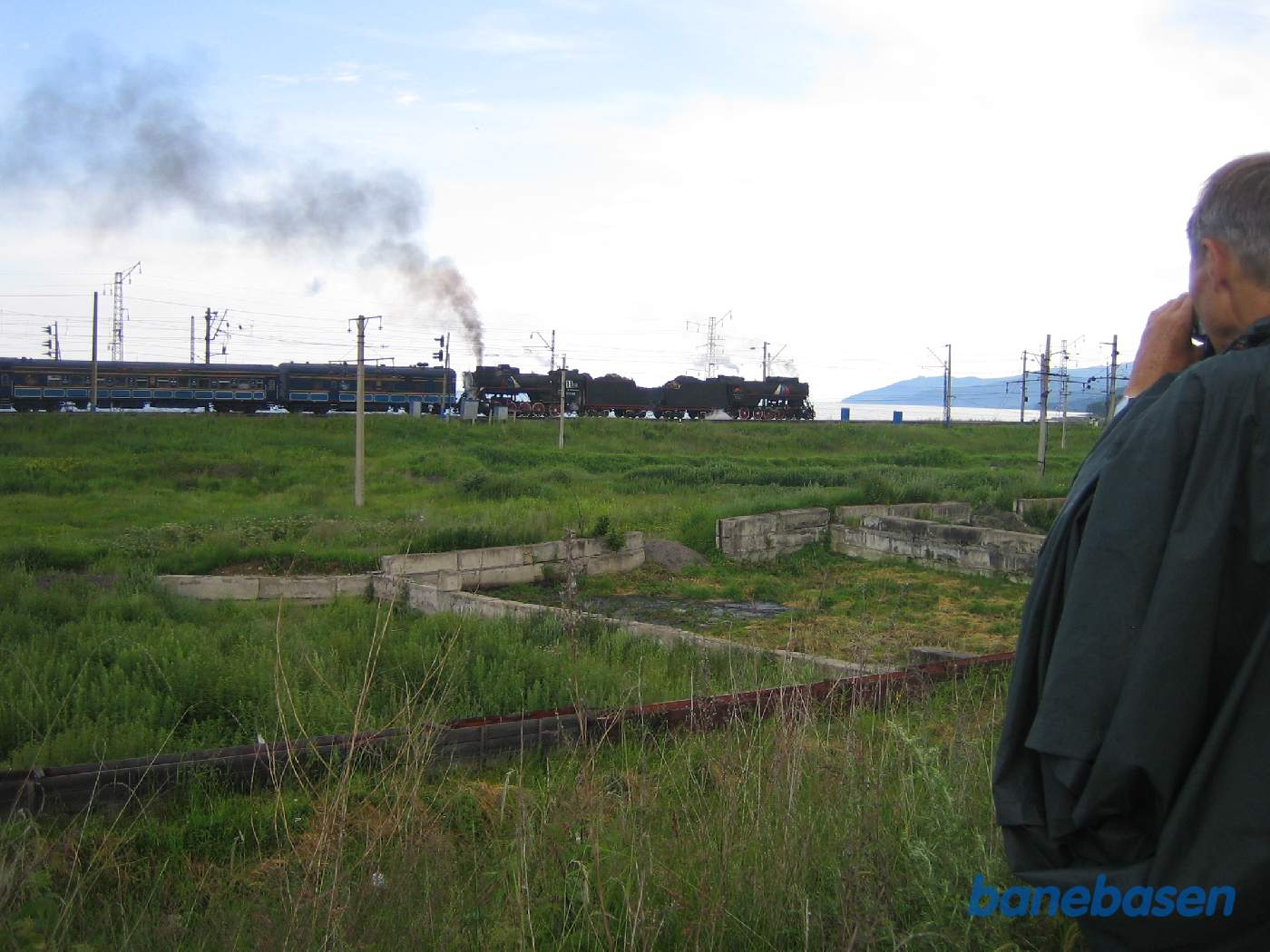 Et turisttog med 2 damplokomotiver fra Port Baikal på vej ind mod Sludyanka station, Baikal søen bag toget