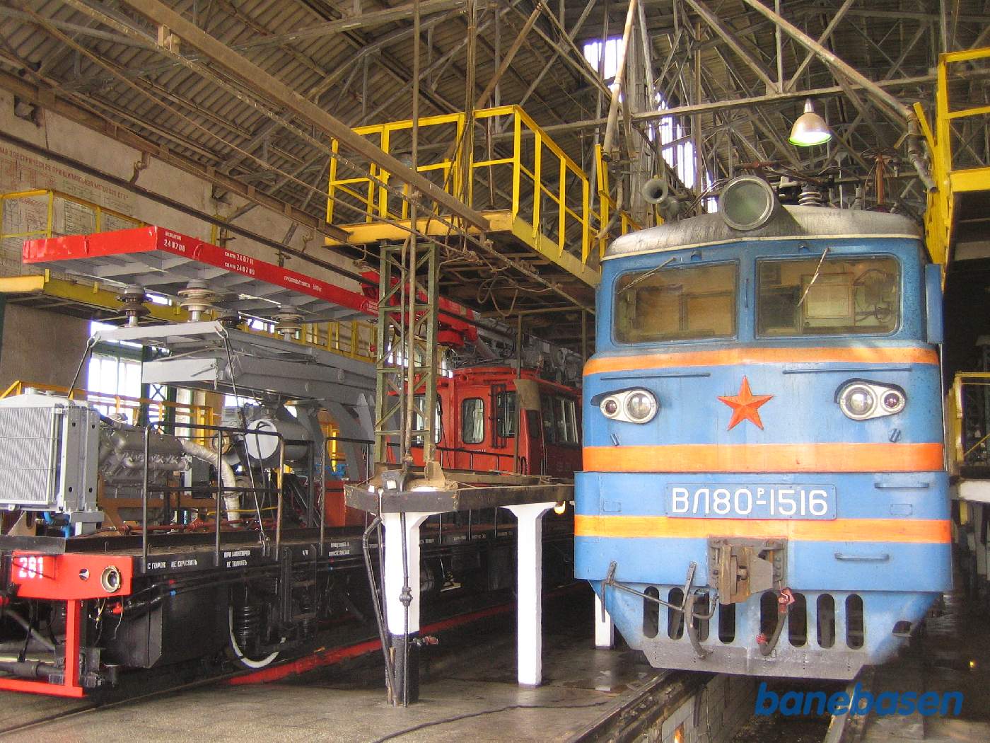 Et elektrisk lokomotiv inde i værkstedet og et arbejdskøretøj i det andet spor