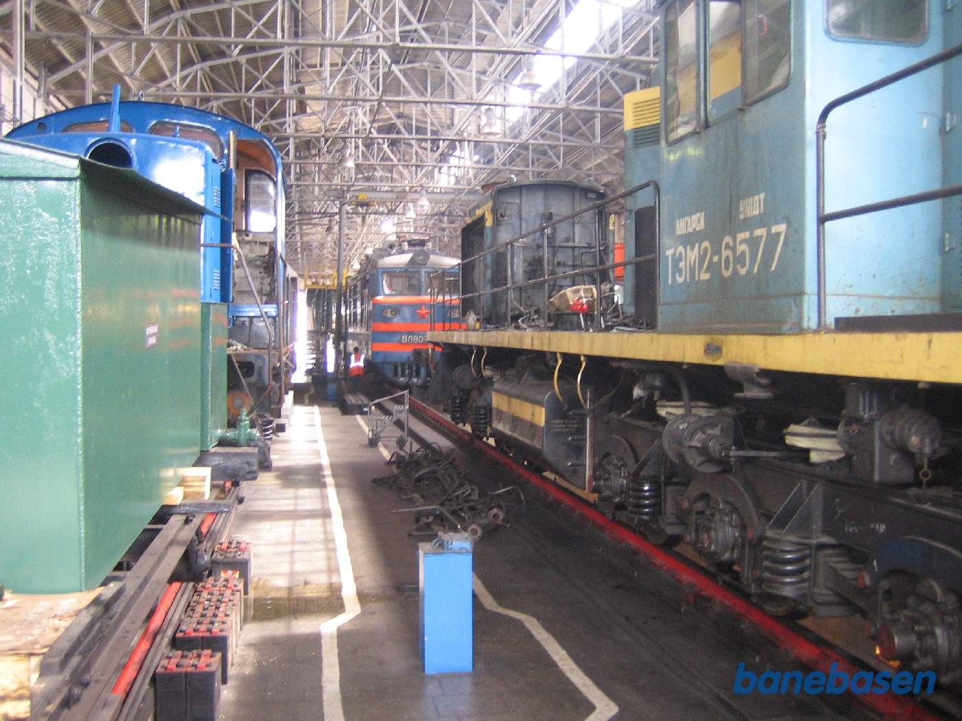 Et adskilt diesel lokomotiv inde i værkstedet og et elektrisk lokomotiv længere fremme