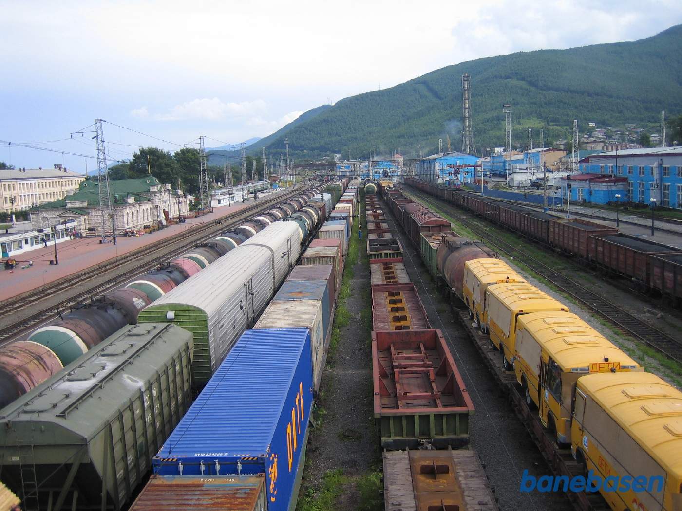 Et vue ned over stationsområdet med de mange ventende godstog, stationsbygningen til venstre og remise og værksted ses ude i horisonten. Billedet er taget fra den lange gangbro over stationsområdet