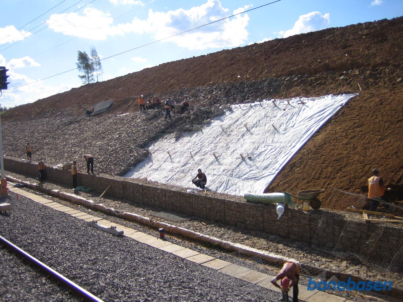 Et arbejdshold i fuld gang med at beklæde skråningen med sten