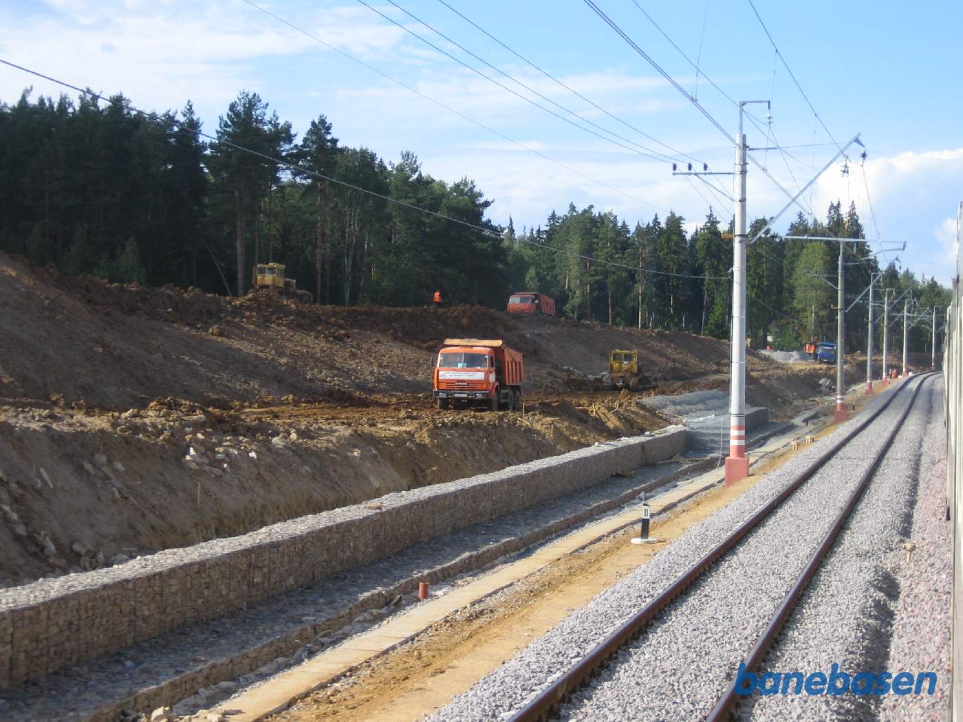 Lastbiler og buldosere arbejder på skråningen langs banen