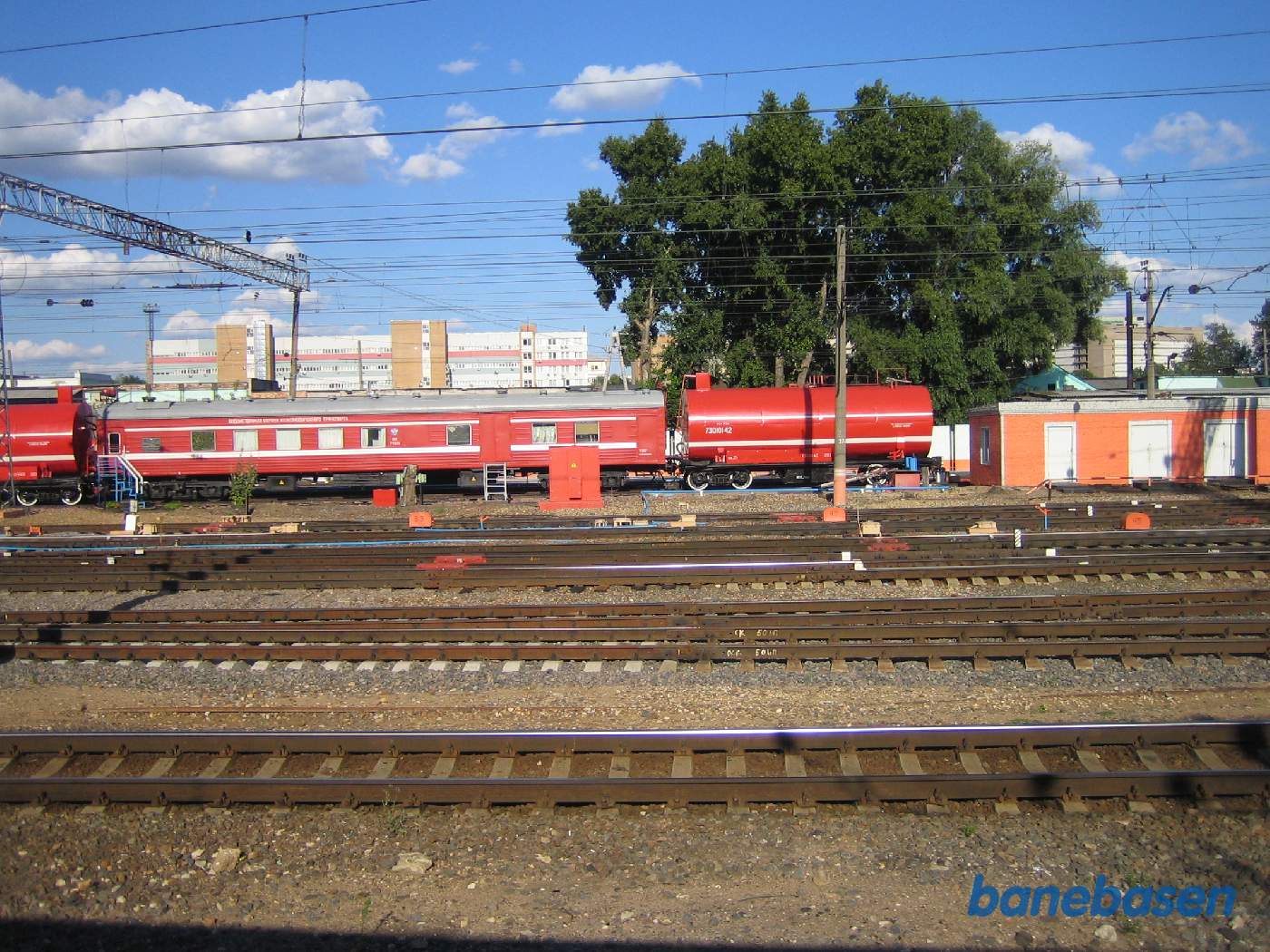 Toget fortsætter ind på stationen og passerer et rødt tog med 2 tankvogne