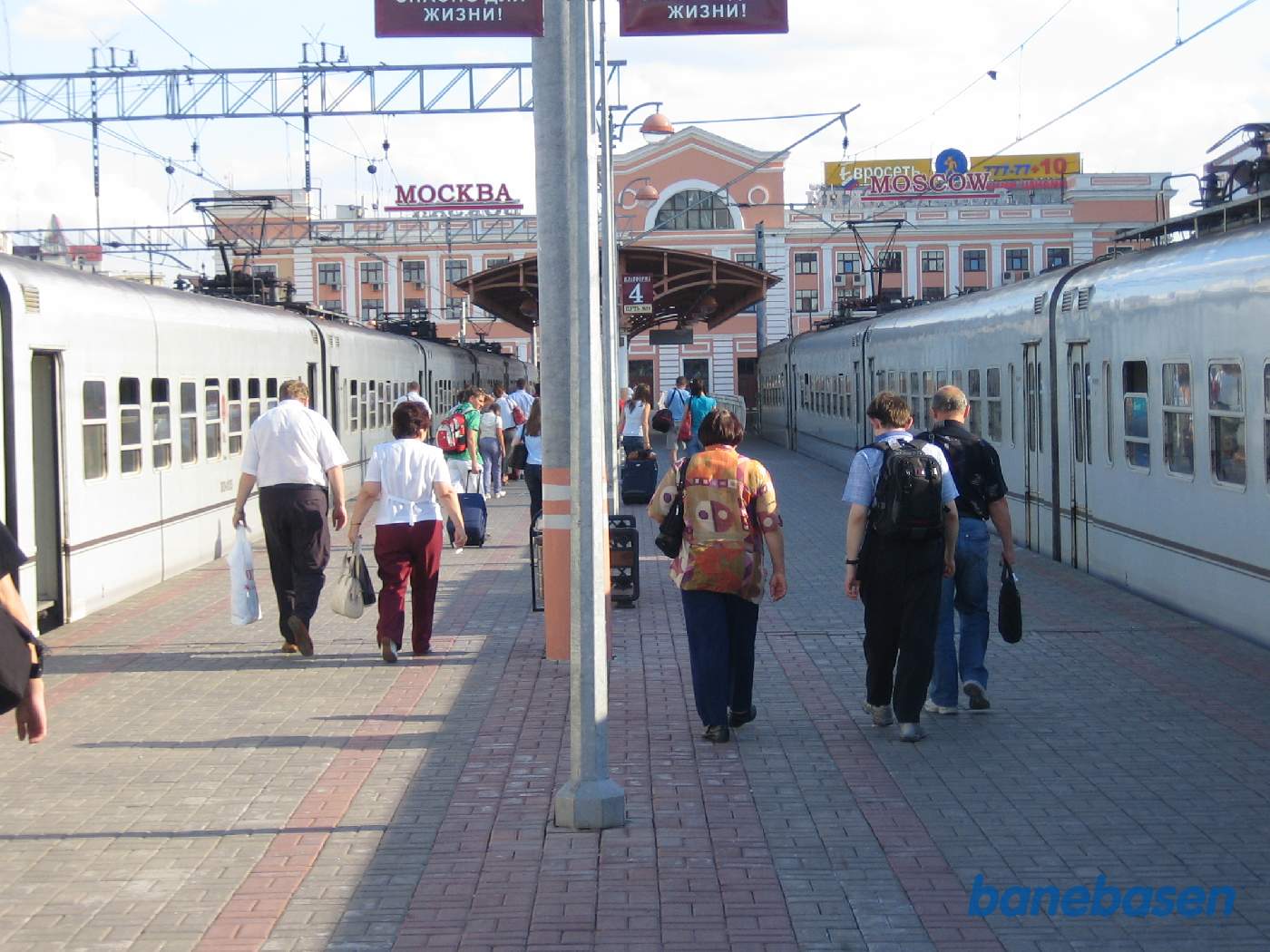 Toget er ankommet til endestationen og passagererne stiger ud. Stationsbygningen for enden af perronen