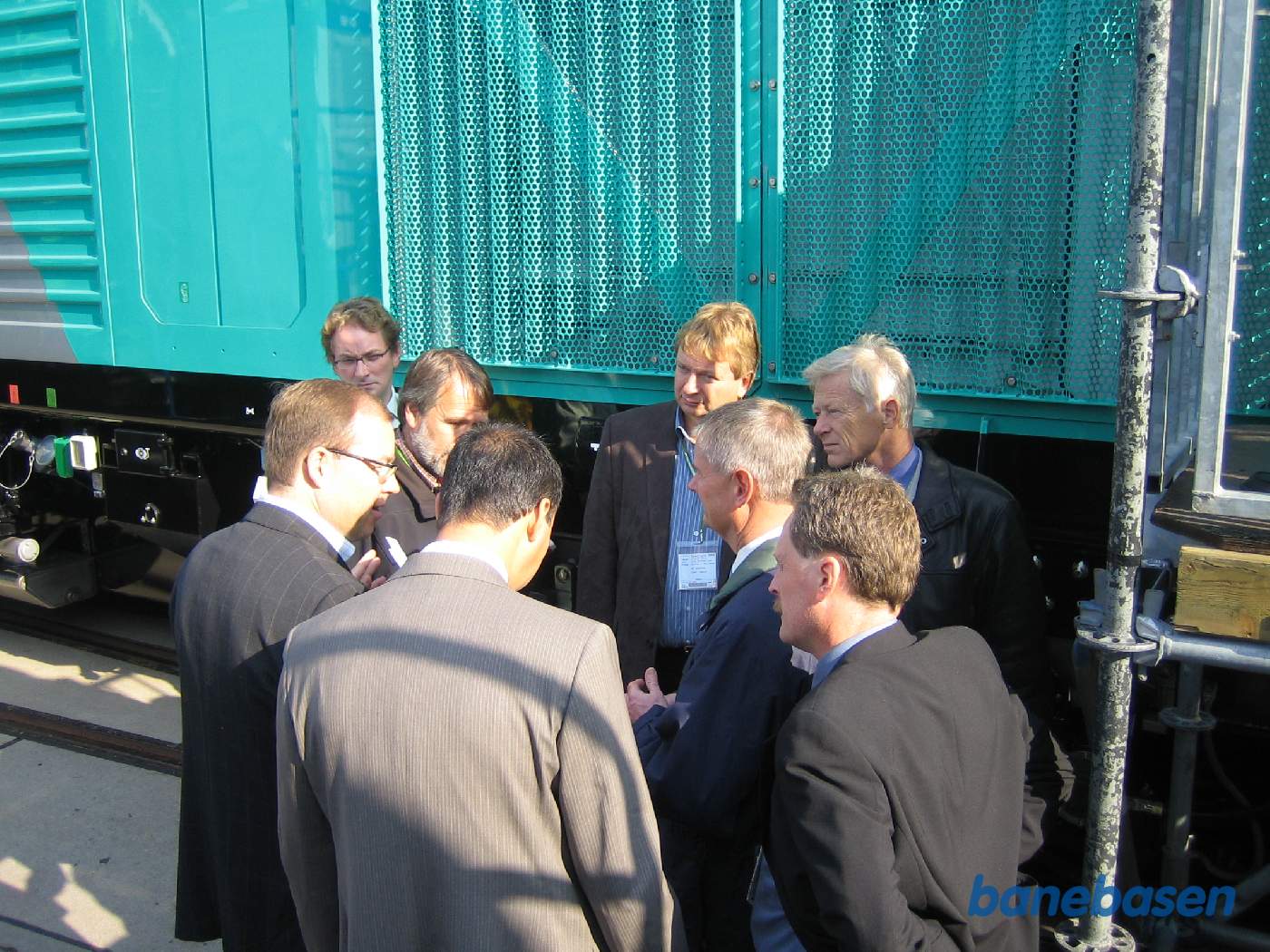 En gruppe gæster står og snakker om lokomotivet bag dem