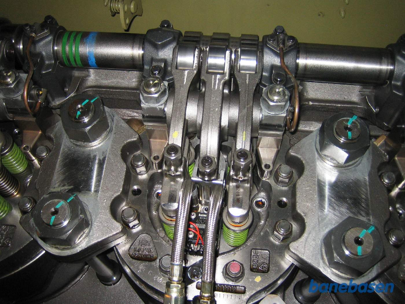 Et af cylinderhovederne i dieselmotoren med vippetøj og brændstofslanger. Dieselpumpen er stangen i midten