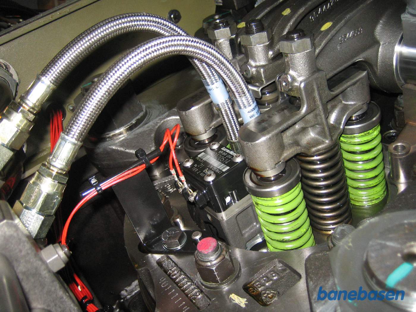 Et af cylinderhovederne i dieselmotoren med vippetøj og brændstofslanger. Dieselpumpen er stangen i midten