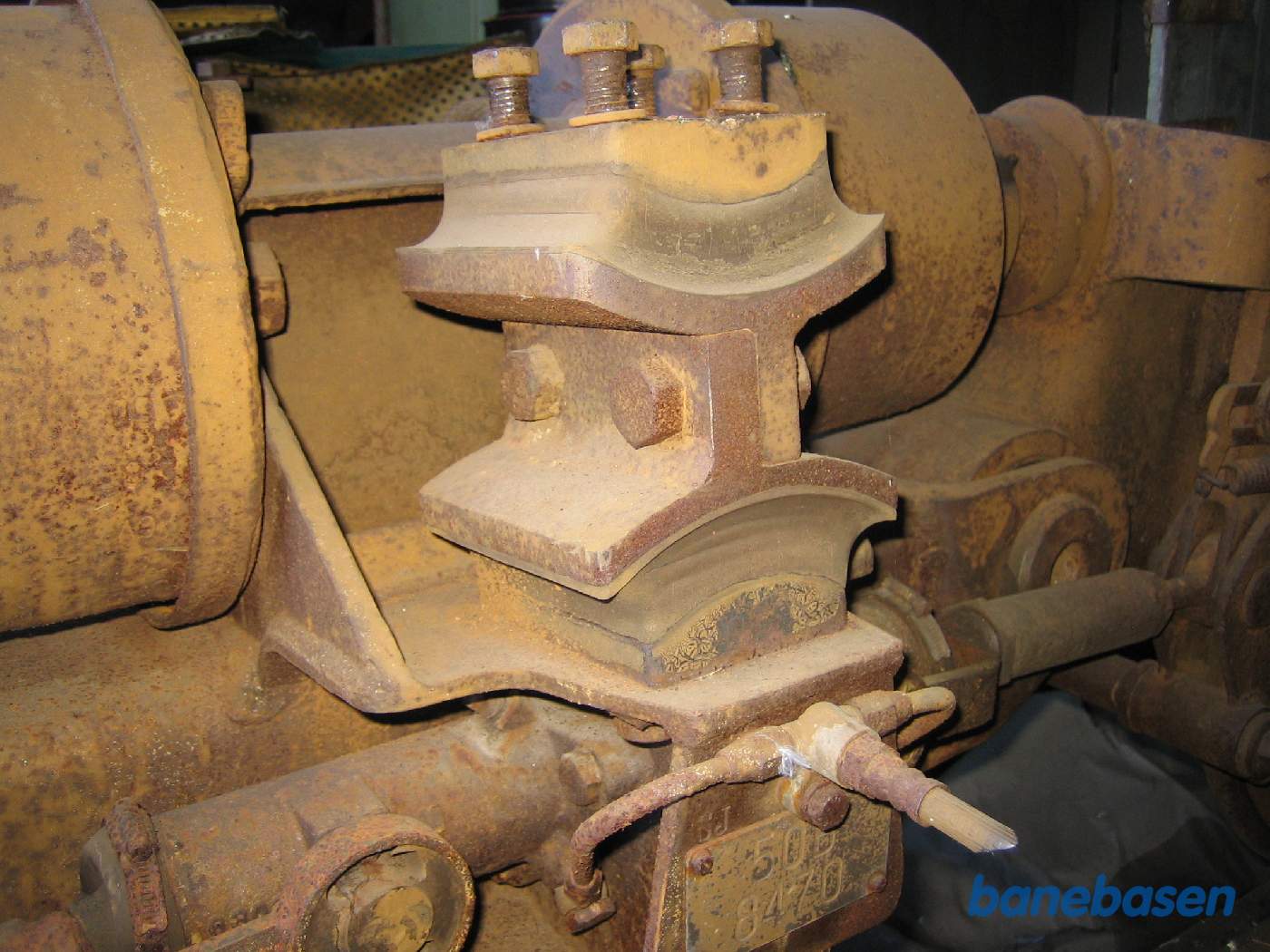 Nærbillede af bogiens befæstelse til vognkassen via de 2 gummiklodser og jernklodsen imellem. Trækket i længderetningen er låset af et "kødben" mellem bogien og vognkassen